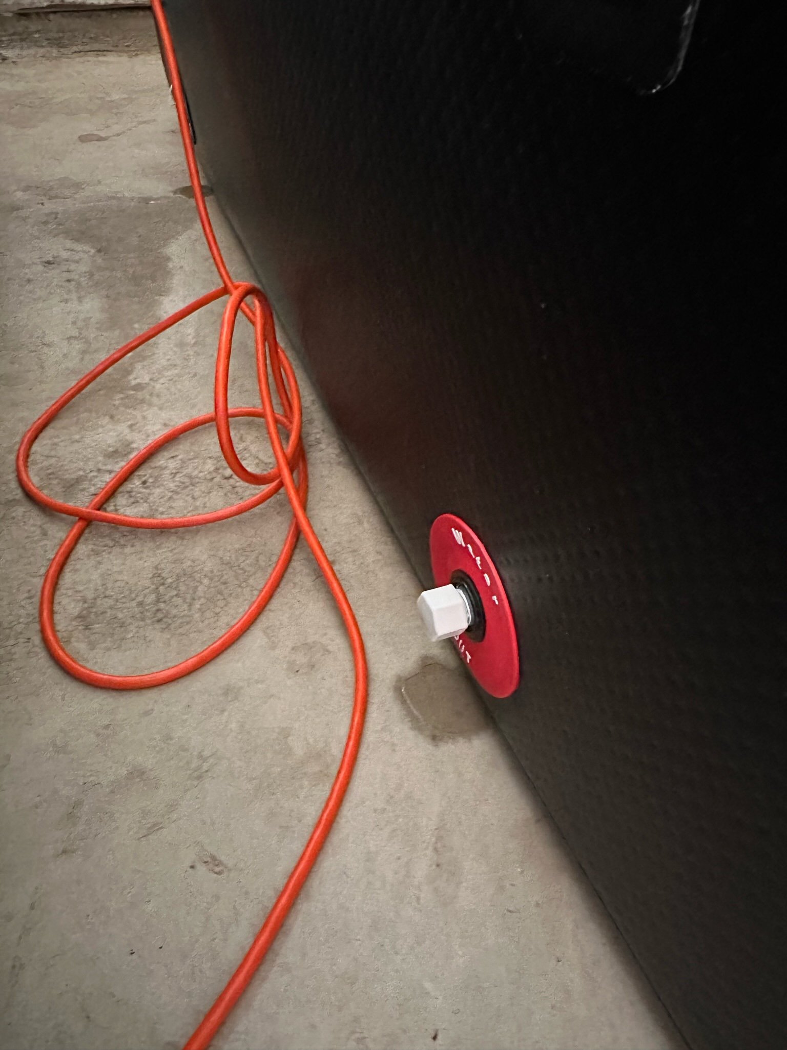 Water gathering beneath the red outlet fitting during a 2023 PlungIT leak and pressure test.